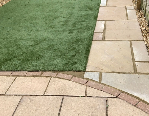 Artificial lawn with newly paved pathway and patio.