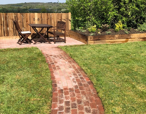 Brickwork pathway to a paved patio and new fencing.